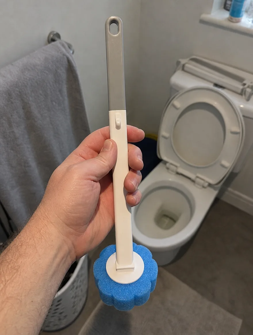 Hand holding up the TossClean wand in a bathroom