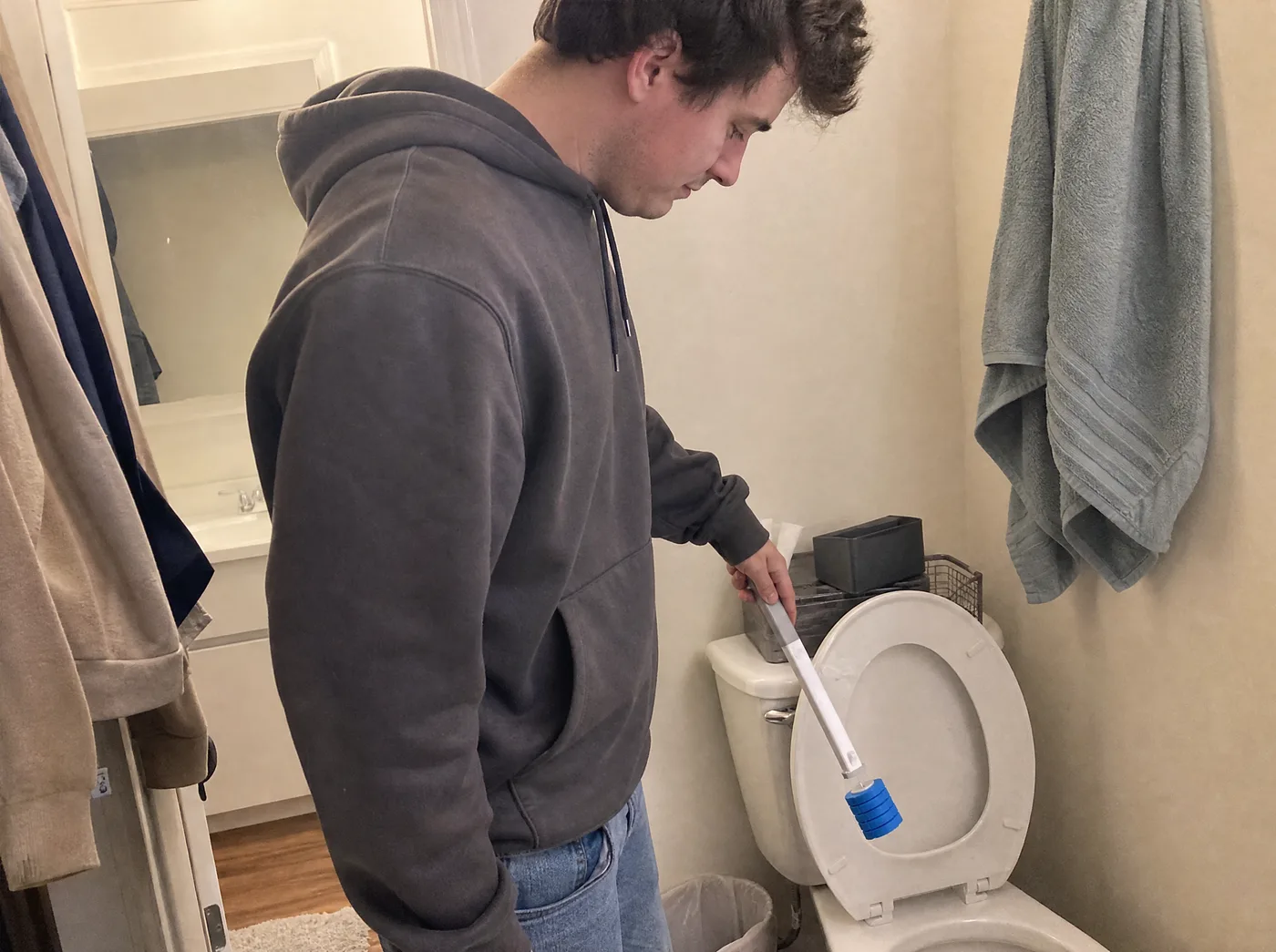 Young man cleaning his apartment toilet with the TossClean wand